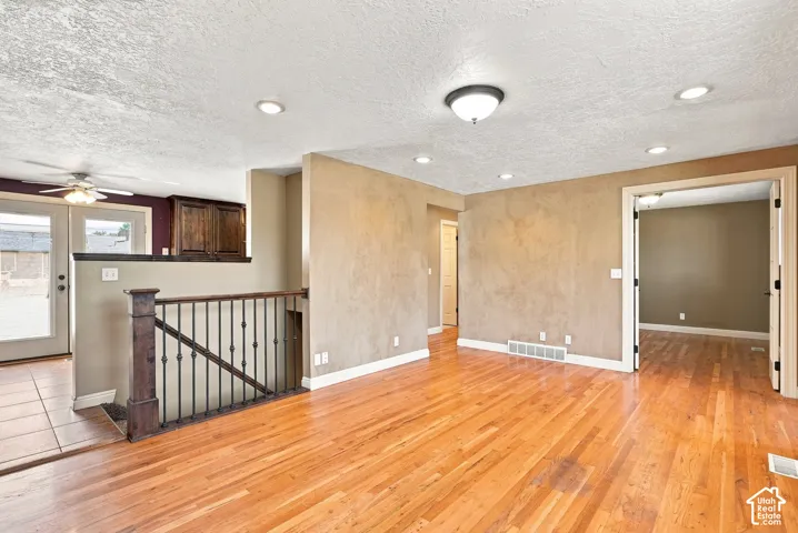 Hardwood flooring throughout, recessed lighting, and a wrought iron railing with wood newel post