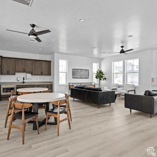 Wood-finish flooring throughout, multiple windows providing natural light, built-in cabinetry with integrated sink, and modern ceiling fans