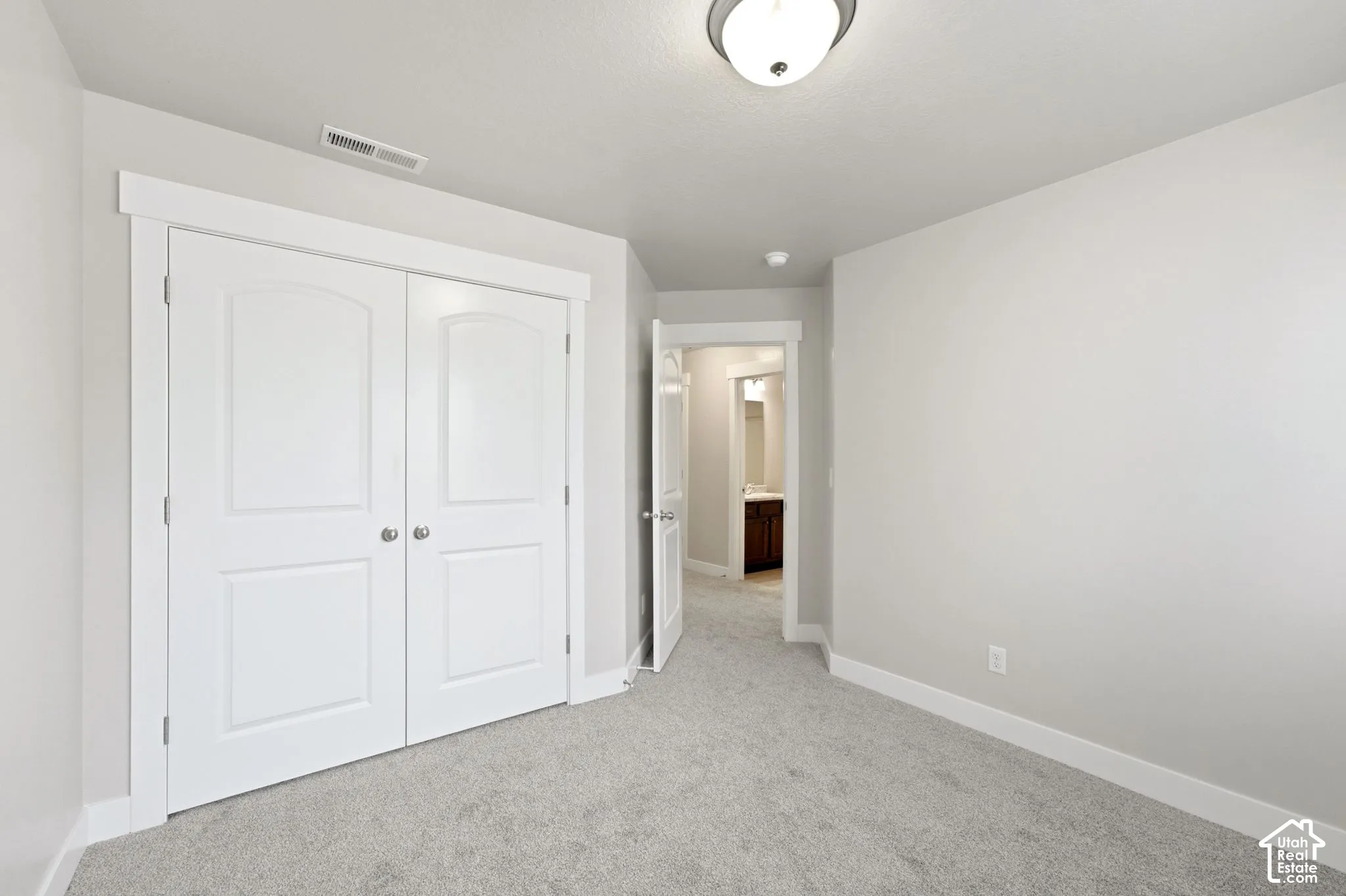Plush carpeting, light gray wall finishes, white trim, and a semi-flush mount ceiling light