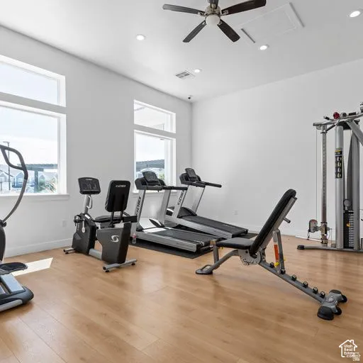 Bright room featuring wood-finish flooring, recessed lighting, and a ceiling fan