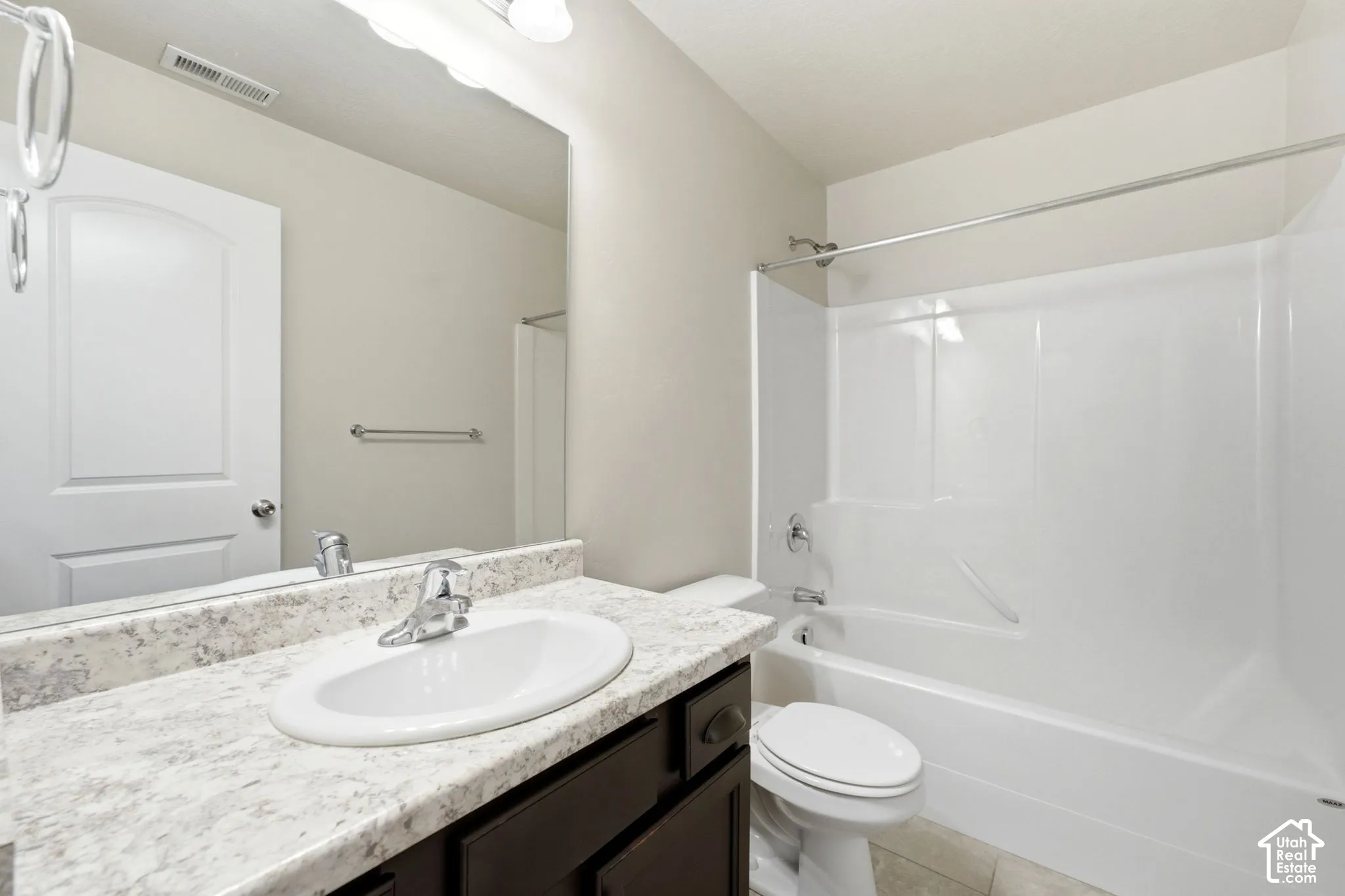 Integrated vanity with a white oval sink, speckled countertop, and dark wood-finish cabinetry