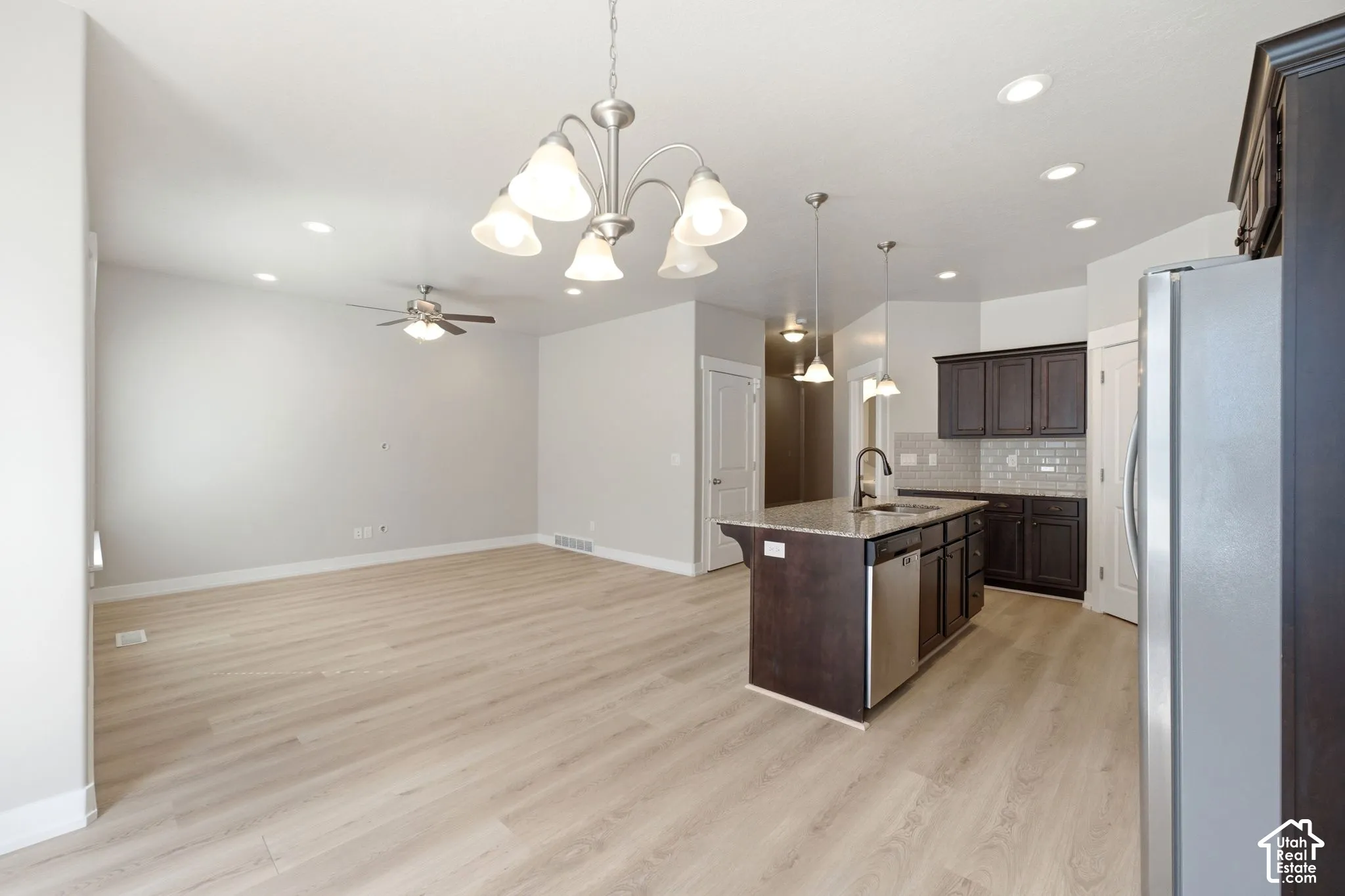 Open-concept layout featuring light wood-finish flooring, recessed lighting, and a ceiling fan