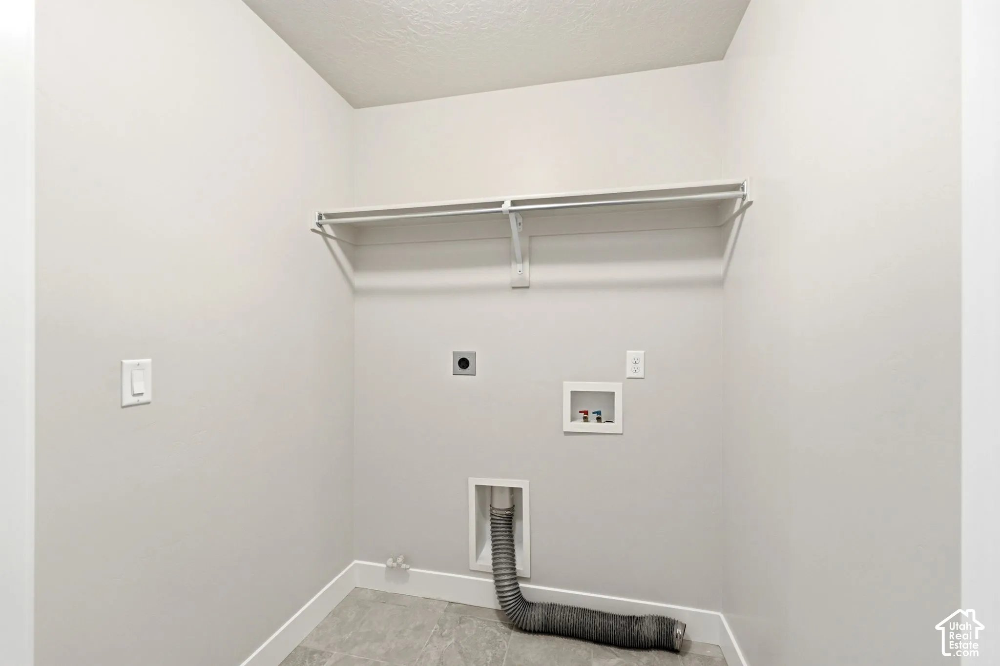 Laundry area featuring a hanging rod, wall-mounted shelving, and utility hookups