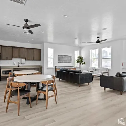 Wood-finish flooring throughout, multiple windows providing natural light, built-in cabinetry with integrated sink, and modern ceiling fans