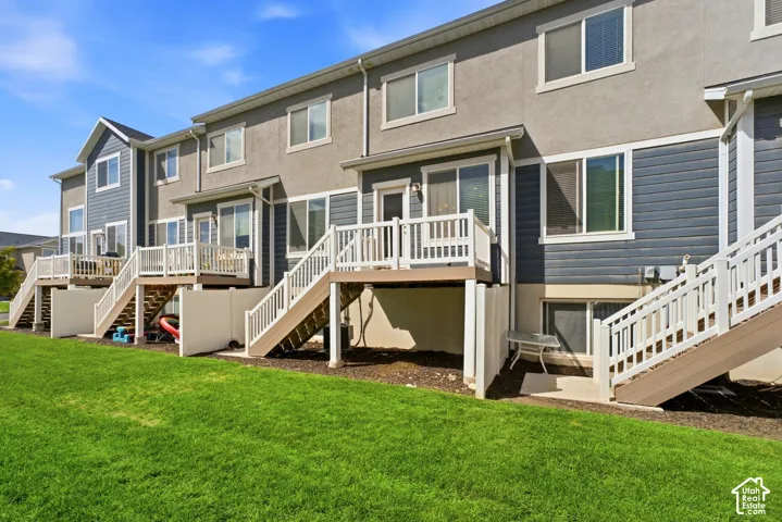 Manicured lawn with multi-level decks featuring white balusters and wood-finish stairs