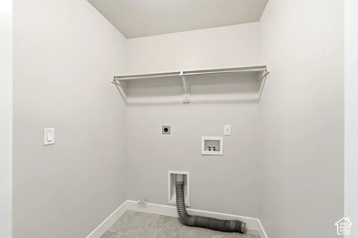 Laundry area featuring a hanging rod, wall-mounted shelving, and utility hookups