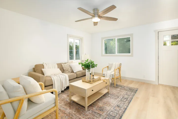 Light wood-finish flooring, white walls, and a ceiling fan with integrated lighting