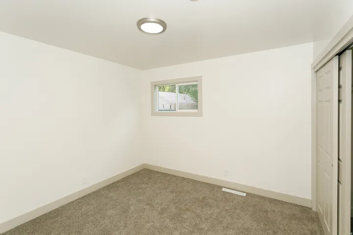 Neutral paint palette, textured carpeting, window with trim, and closet with bi-fold doors