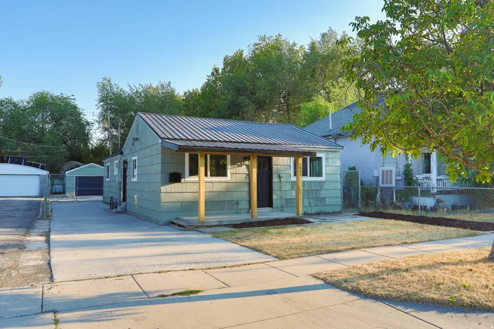 Light green siding exterior with a dark metal roof