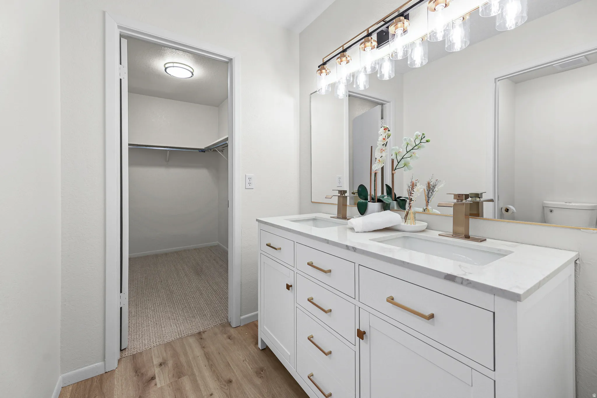 Dual vanity with white cabinetry, gold-finish hardware, and a stone countertop