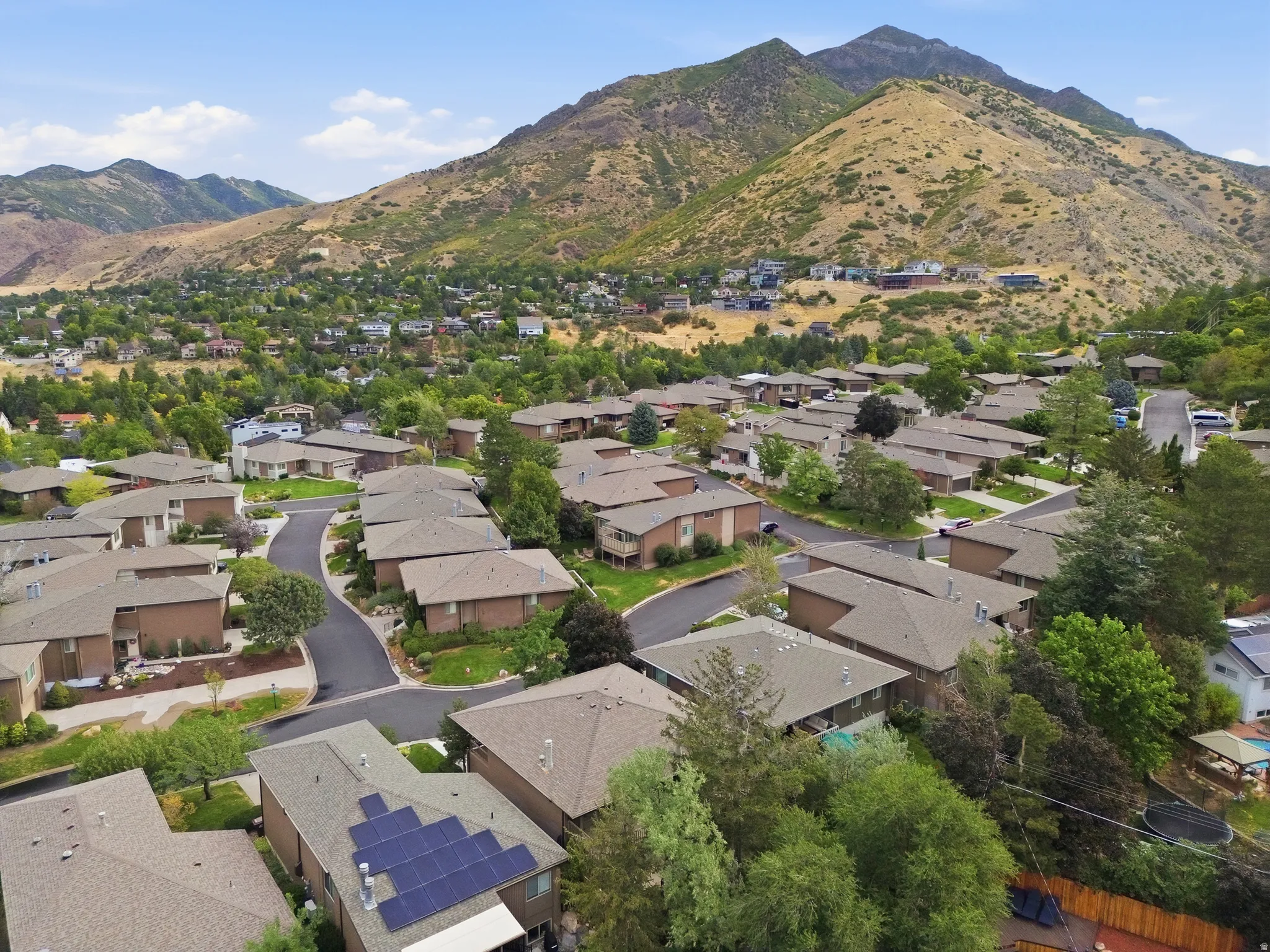 Residential community with varied rooflines and mature landscaping, set against a mountain backdrop