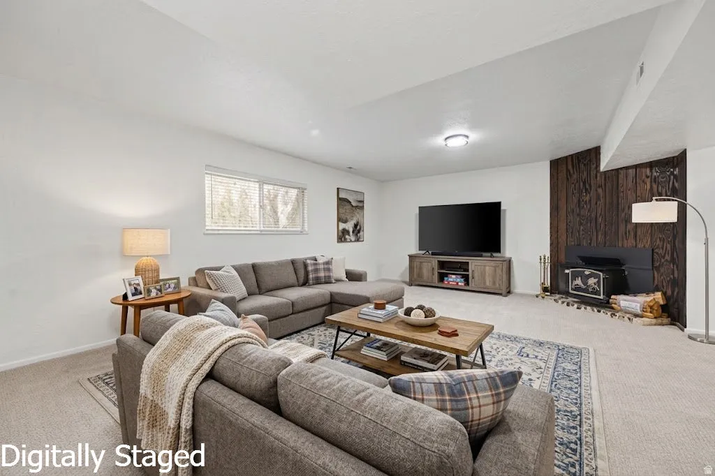 Carpeted living area featuring a prominent wood-paneled accent wall, a wood-burning stove with a hearth, and a window with blinds