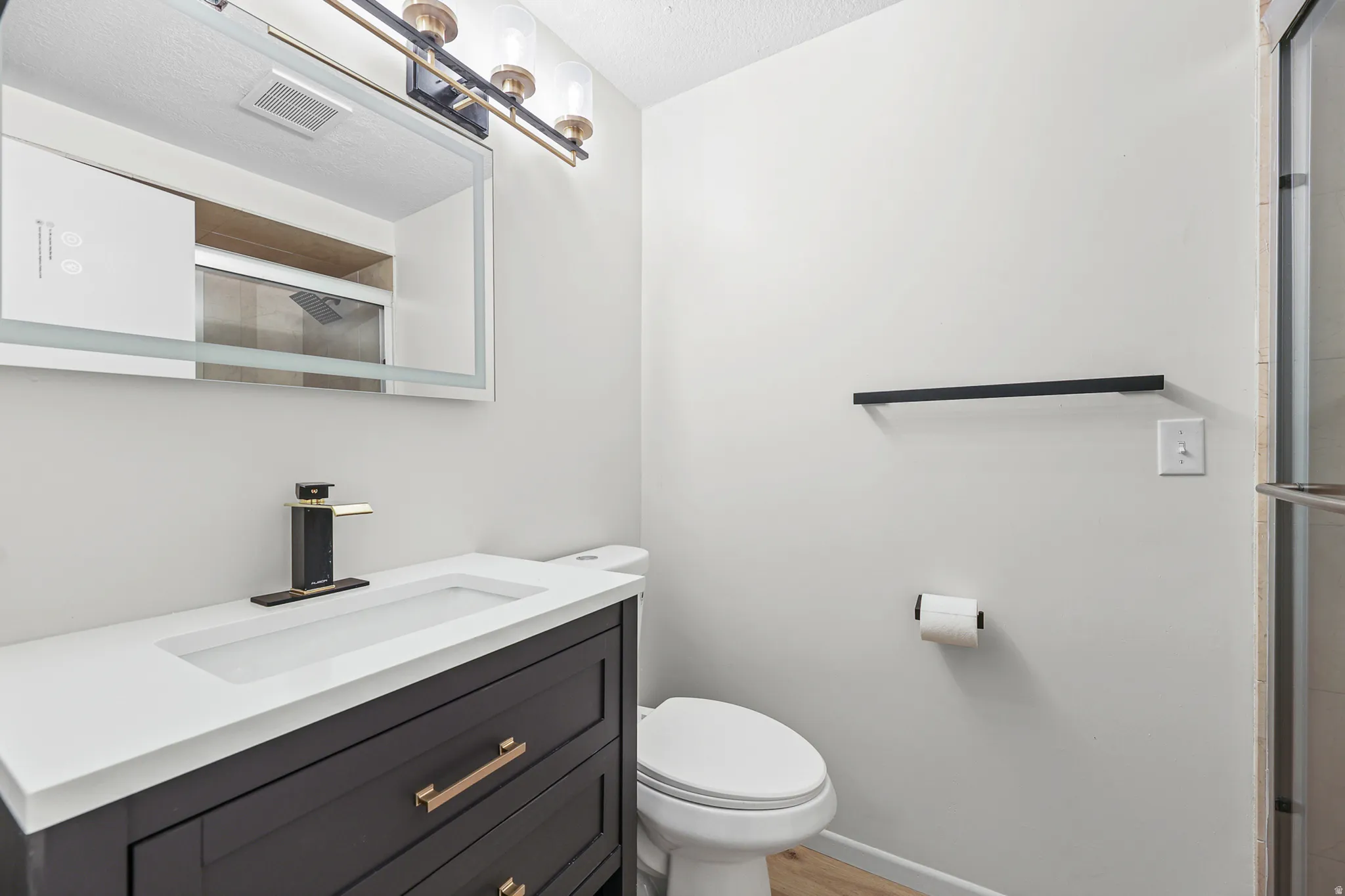 Vanity with a white integrated sink, dark cabinetry, and bronze-finish hardware