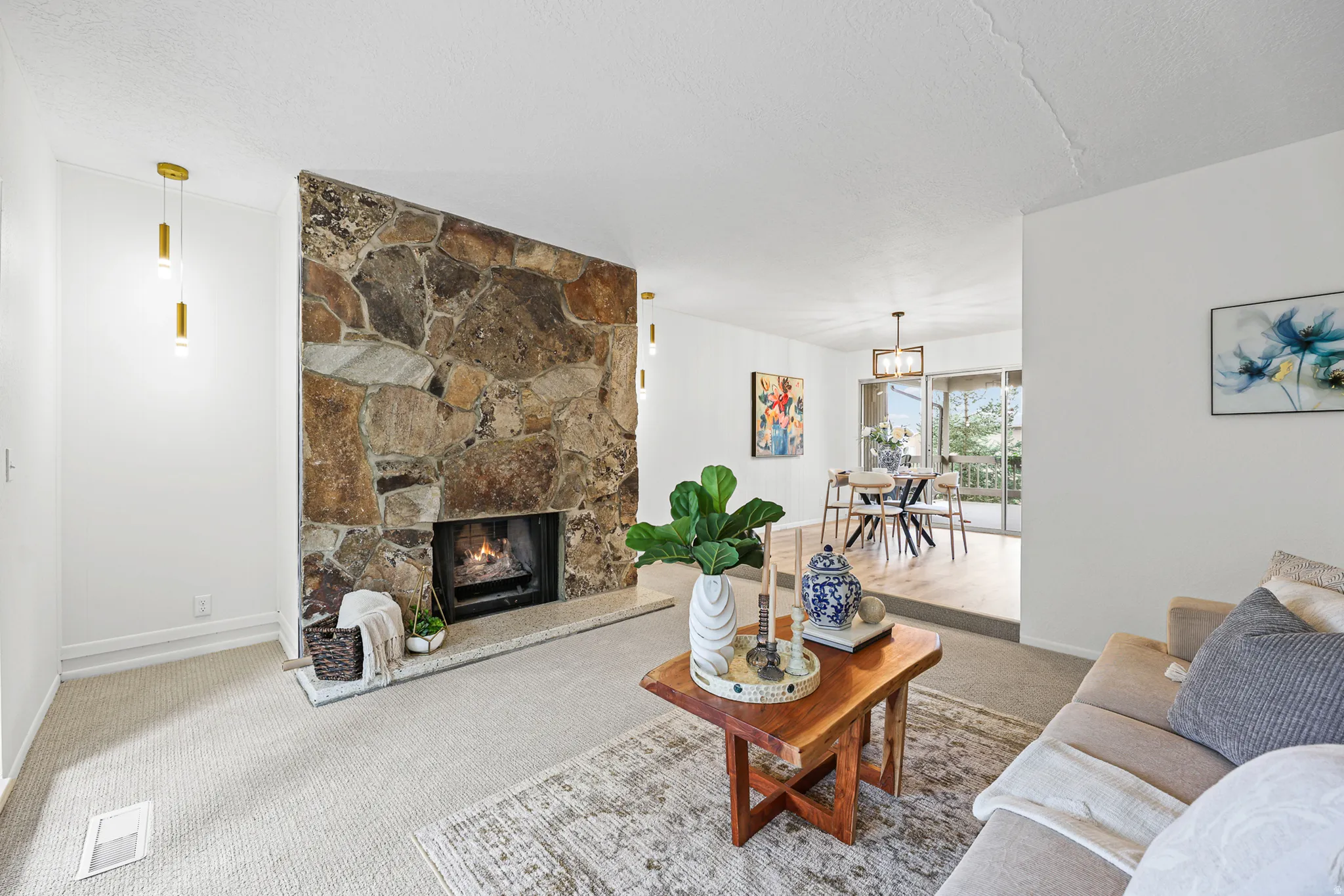 Stone-clad fireplace with hearth, recessed wood-burning firebox, and dual pendant lighting