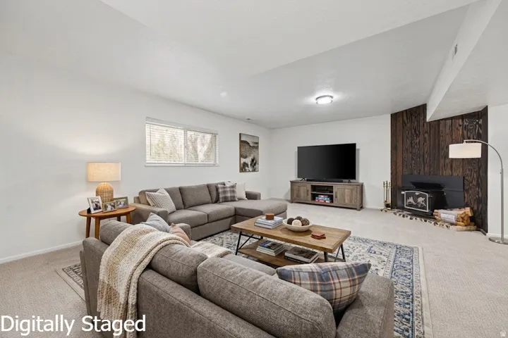 Carpeted living area featuring a prominent wood-paneled accent wall, a wood-burning stove with a hearth, and a window with blinds