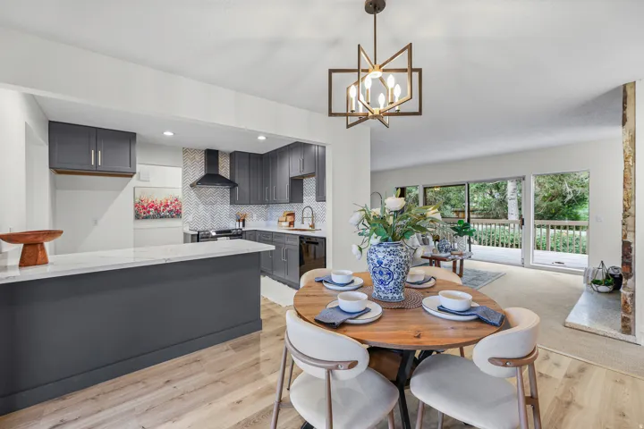 Kitchen with gray cabinetry, white countertops, herringbone tile backsplash, and a built-in range hood