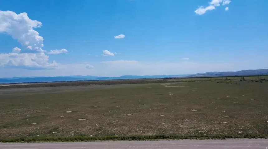 Expansive open land with distant mountain ranges and a clear blue sky