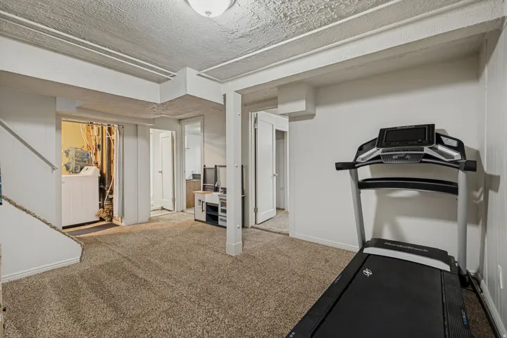 Carpeted room with a textured ceiling, a built-in laundry area, and interior doors