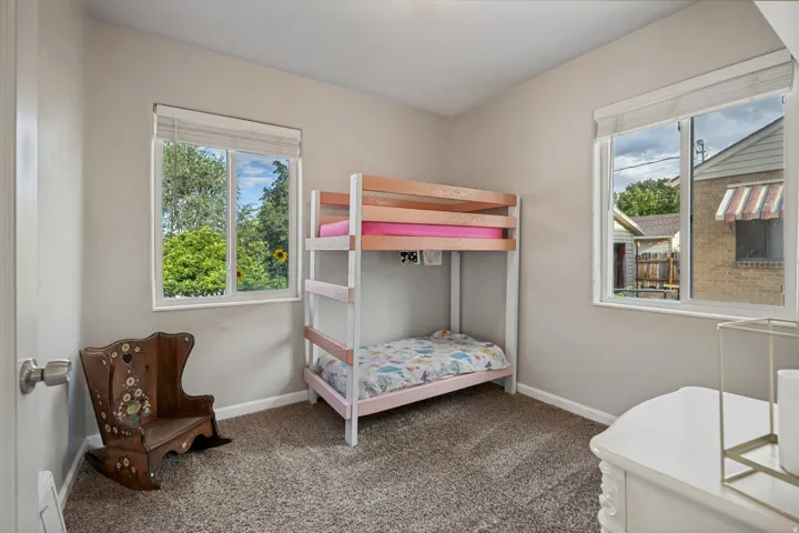 Neutral wall paint, plush carpet flooring, and multiple windows with roller shades