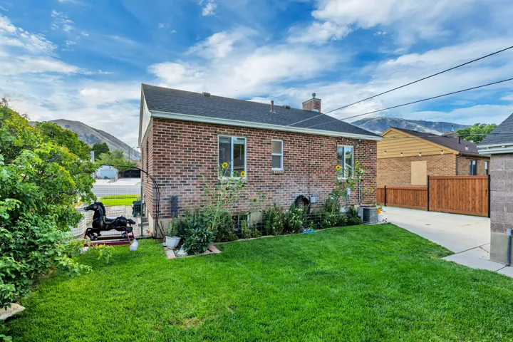 Brick exterior, gabled roof, mature landscaping, paved driveway, and perimeter fencing