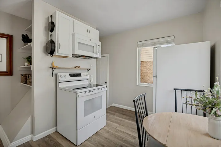 Kitchen featuring white cabinetry, built-in microwave, electric range, and wood-finish flooring