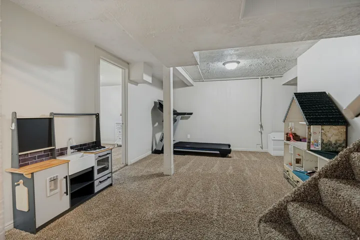 Carpeted floor, neutral wall paint, overhead lighting, partially finished ceiling, open doorway