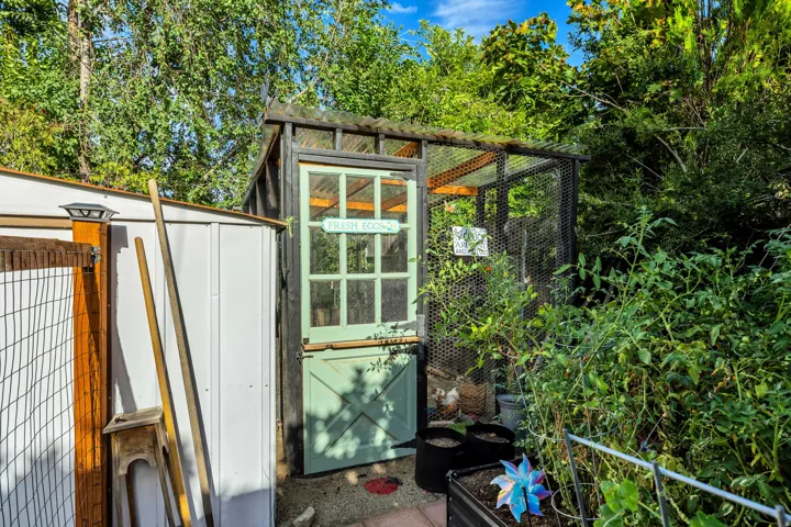 Outdoor storage shed with a metal exterior, wooden gate with solar lighting, and a screened enclosure with a glass-paned door