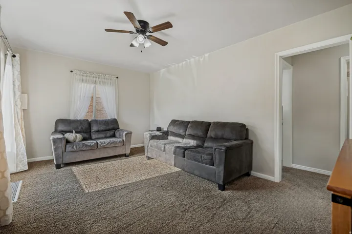 Neutral wall tones, ceiling fan with light fixture, and plush carpeting throughout