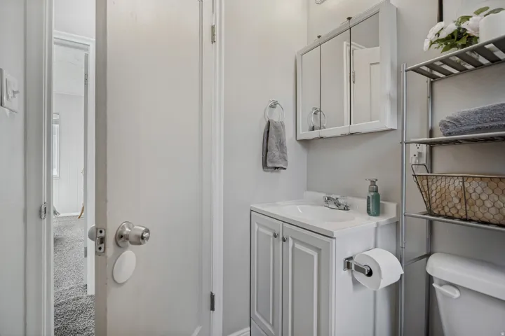 White vanity with a rectangular sink, wall-mounted medicine cabinet, and chrome faucet