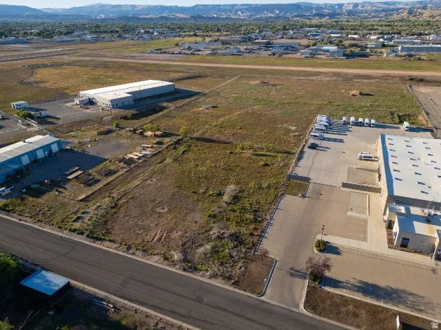 Expansive land parcel with surrounding commercial structures and distant mountain range