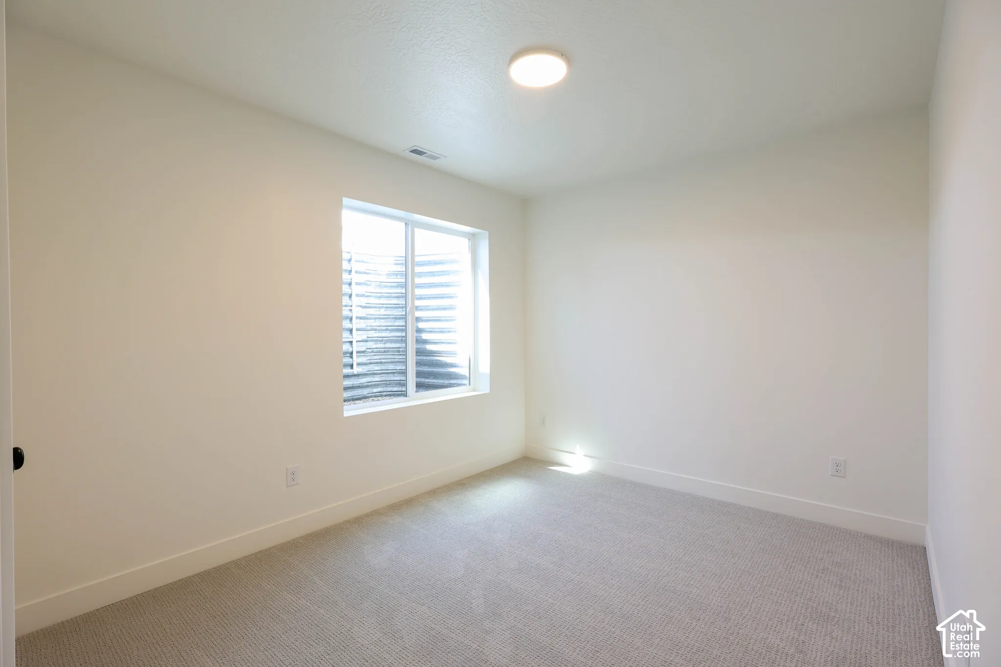 Recessed window with a window well, light-toned carpeting, white walls, and a ceiling-mounted light fixture