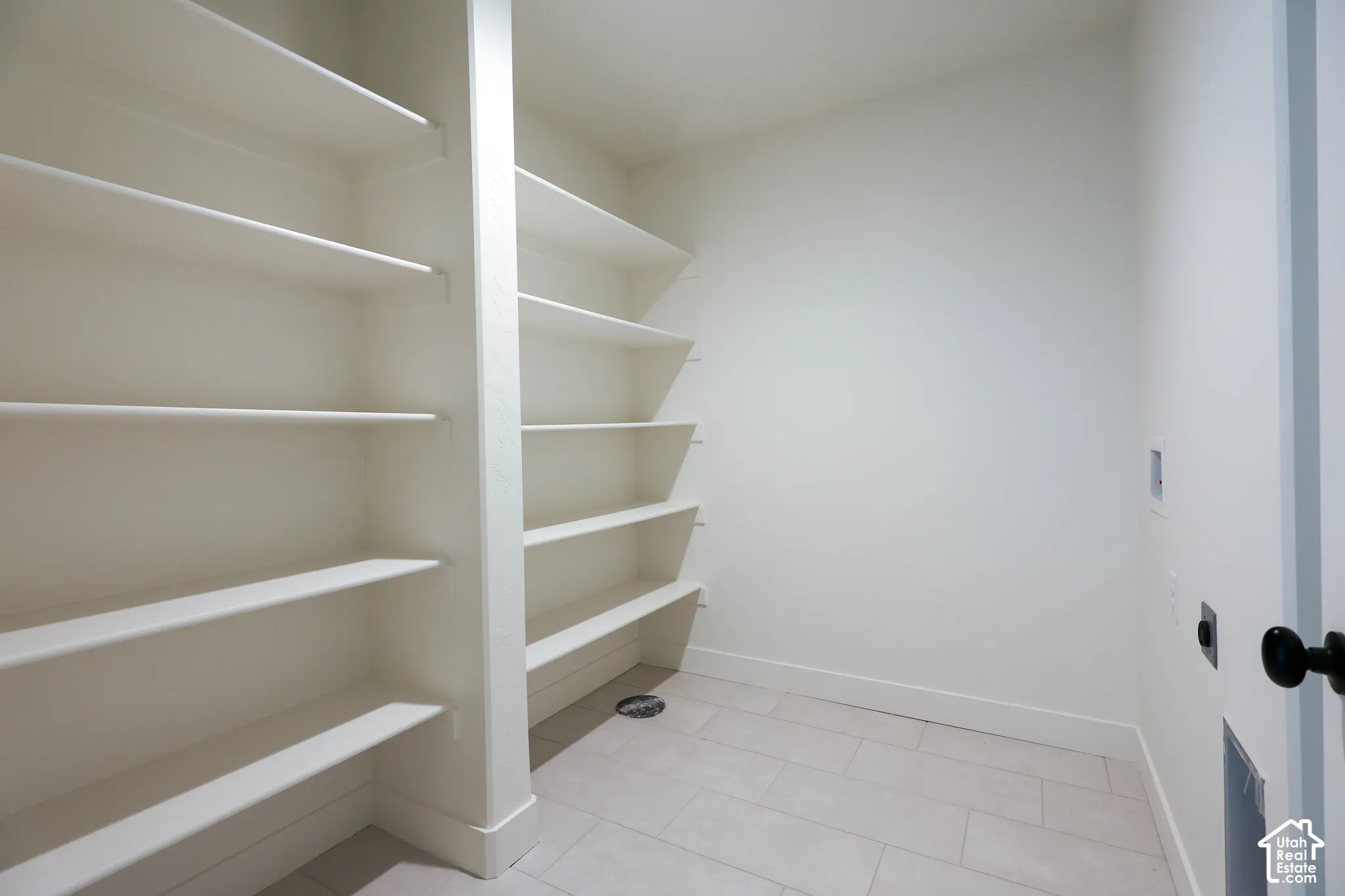 Basement laundry room with Built-in shelving, ample storage capacity, light-toned walls, and a tiled floor