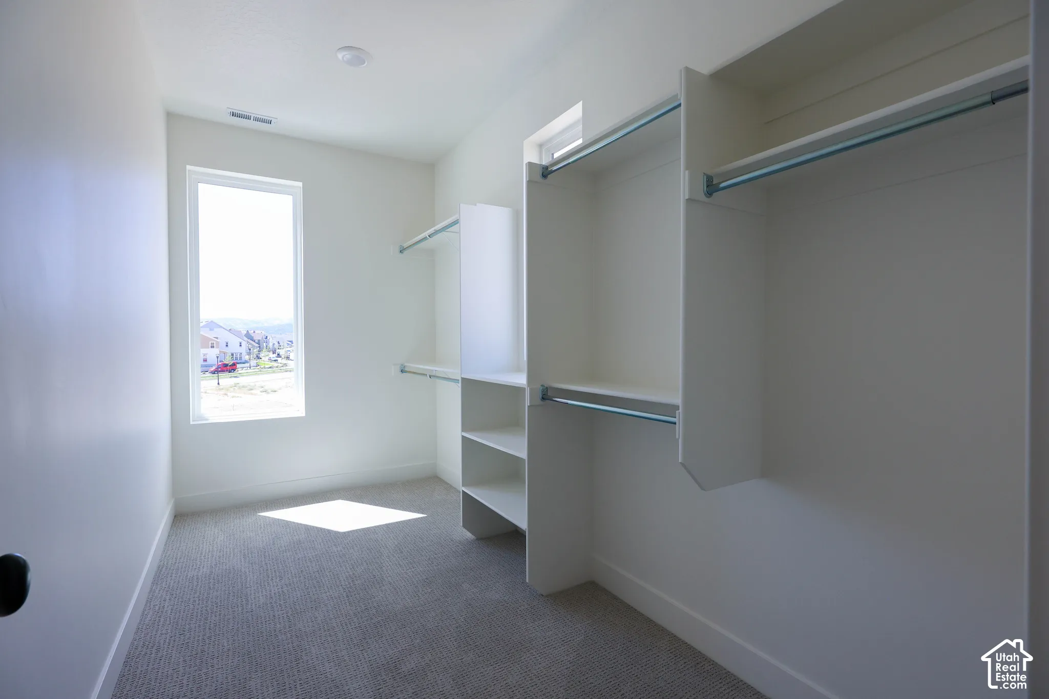 Built-in shelving and hanging rods, recessed ceiling lighting, light-colored carpeting, and a window