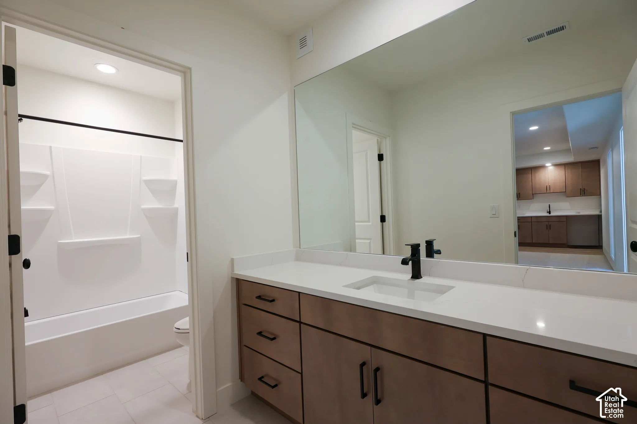 Single vanity with a rectangular undermount sink, solid surface countertop, and dark-finished faucet