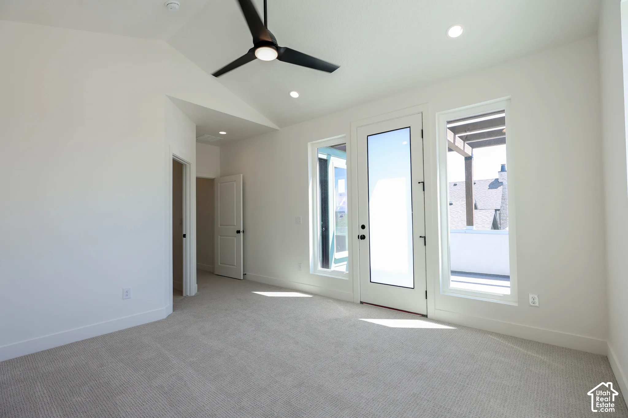 Primary bedroom with access to Balcony and Vaulted ceiling with a ceiling fan, recessed lighting, carpet flooring, and a glass-paneled door with sidelights