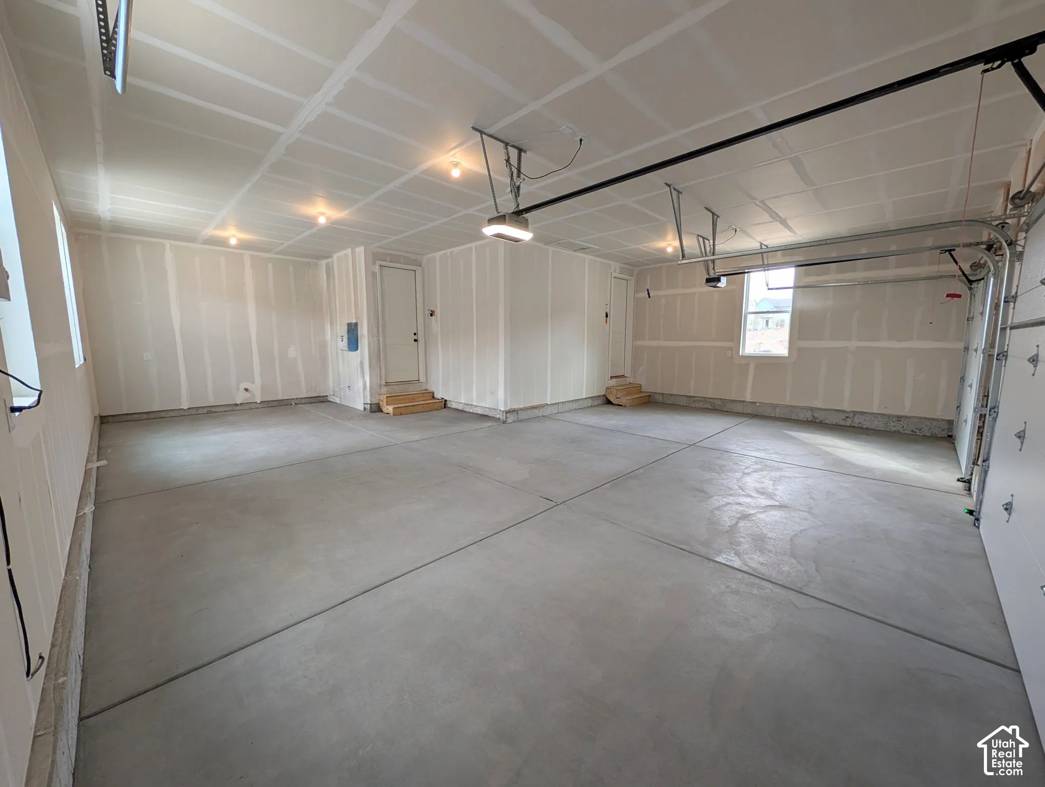 Spacious 3 car garage featuring a concrete floor, built-in overhead lighting, and multiple windows for natural illumination