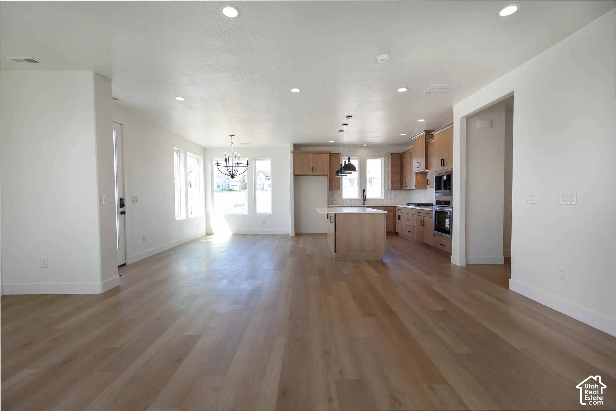 Open-concept living space featuring wood-finish flooring, recessed lighting, and multiple windows