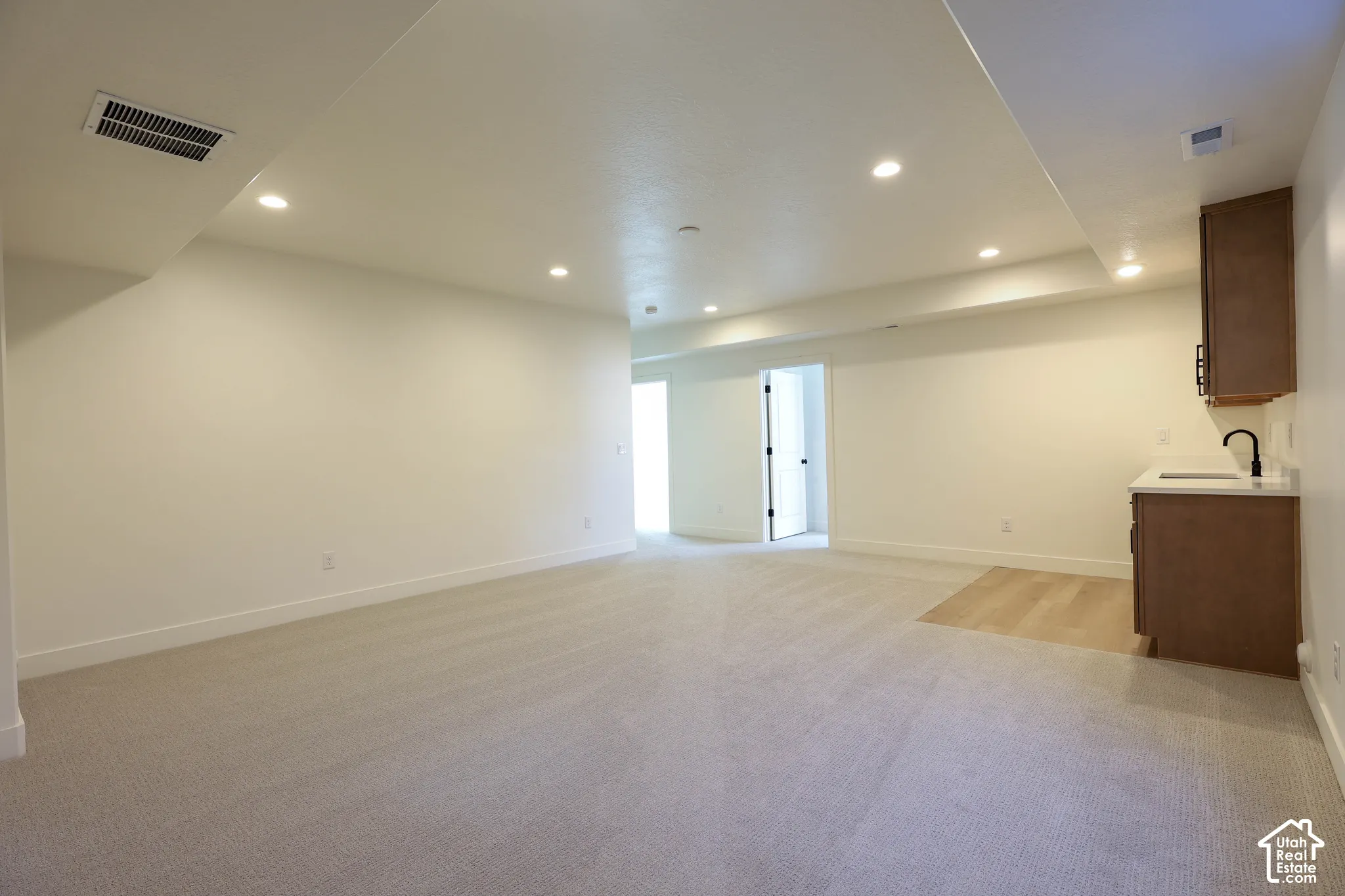 Spacious open-concept room featuring recessed ceiling lighting, light wood-finish flooring, and freshly painted white walls