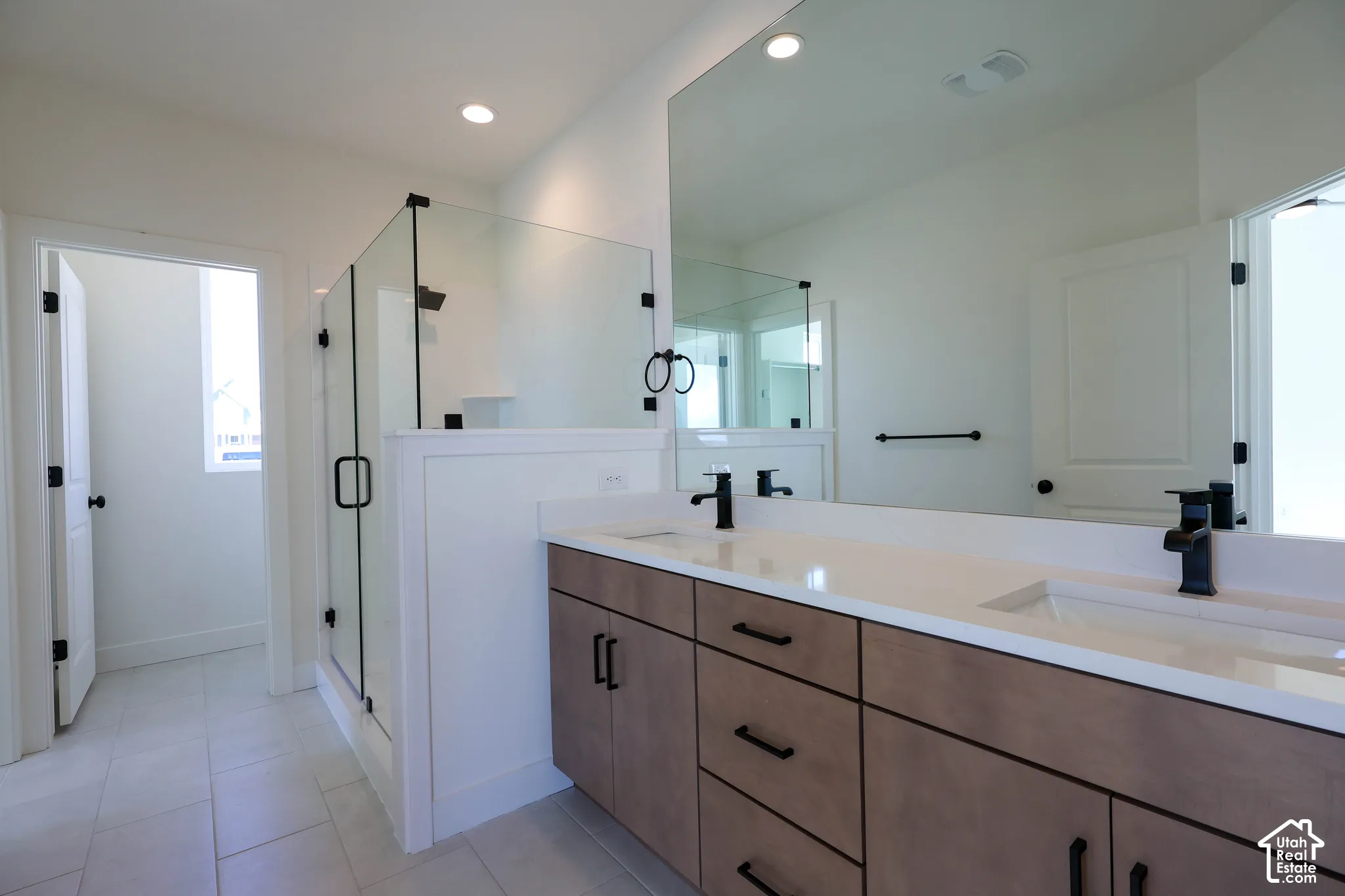 Primary bathroom with Dual vanity with integrated sinks, light-toned cabinetry, and matte black fixtures