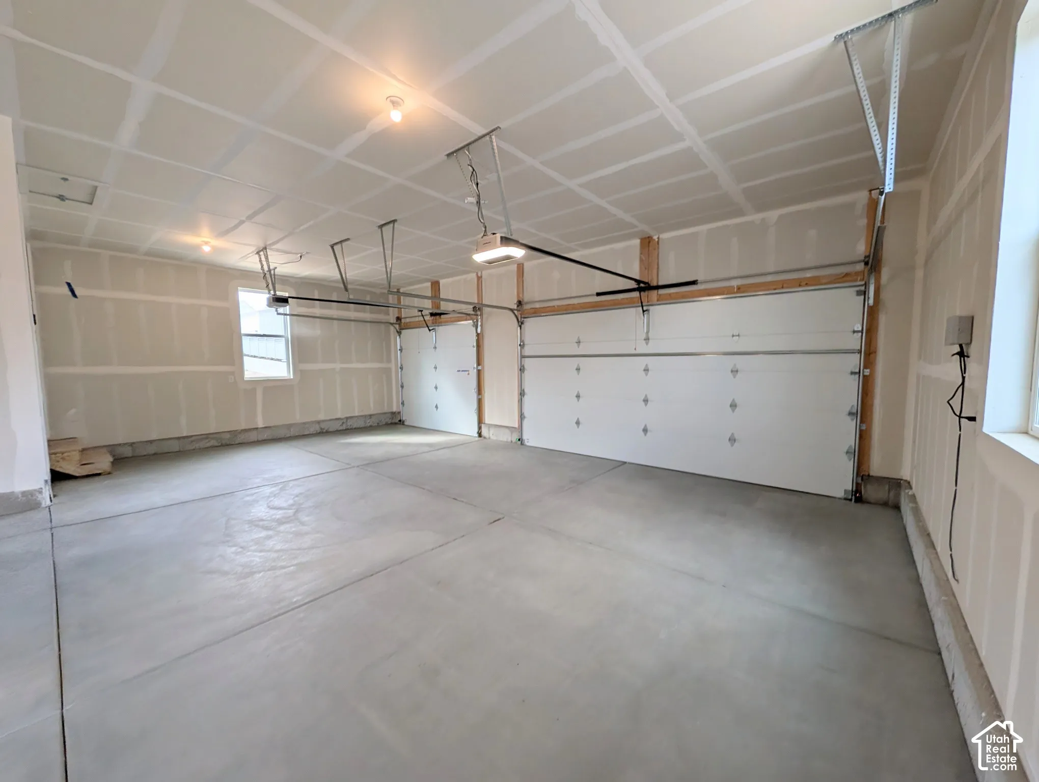 Spacious 3 car garage with exposed drywall, concrete flooring, and a window for natural light