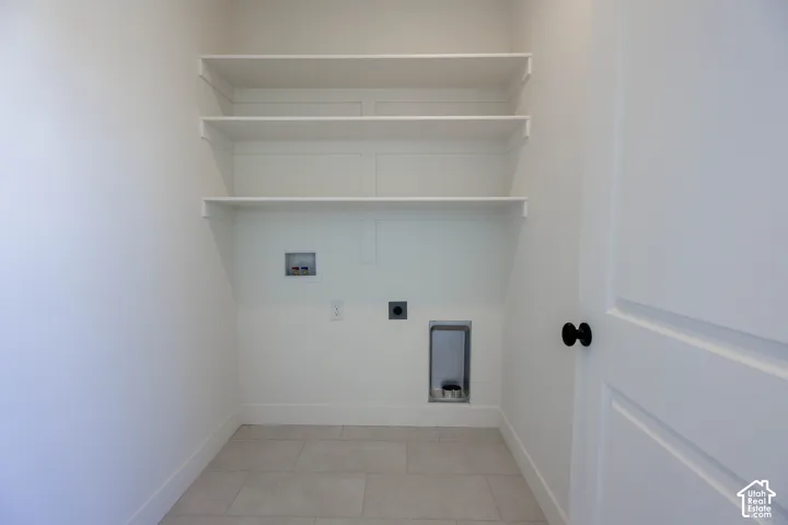 Upper level laundry room with White walls with integrated shelving, tile flooring, and a flat panel door with matte black hardware