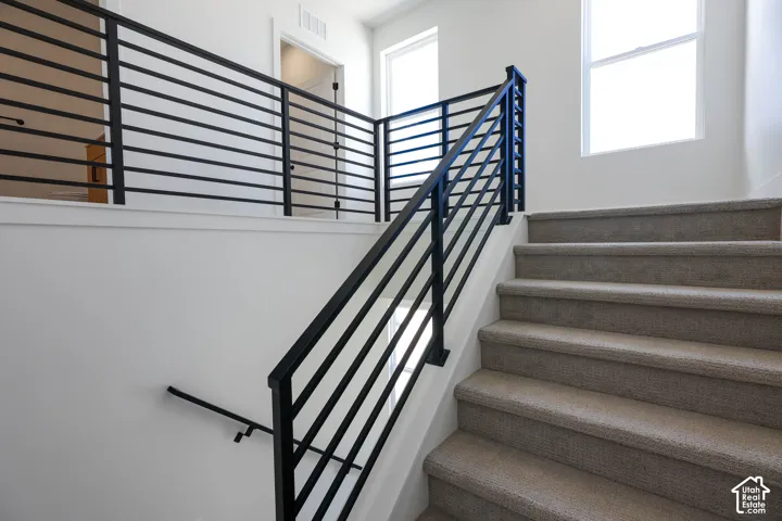 Staircase featuring carpeted treads, a black metal horizontal bar railing, and a coordinating handrail