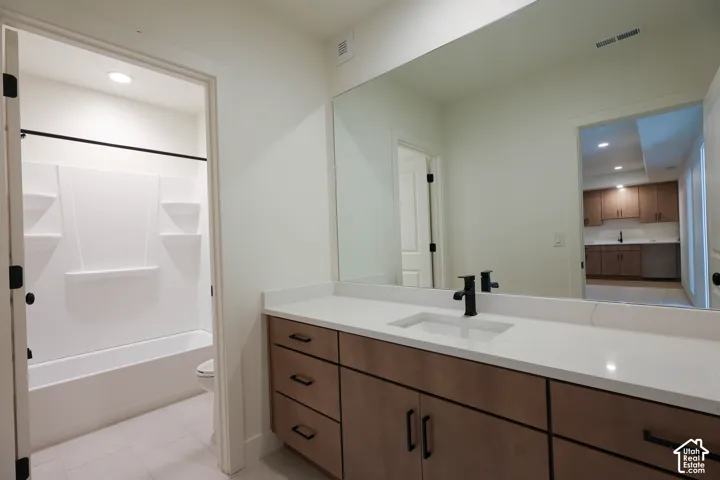 Single vanity with a rectangular undermount sink, solid surface countertop, and dark-finished faucet