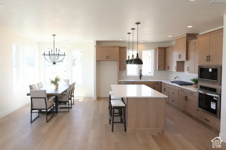 Open-concept space featuring wood-finish flooring, a kitchen island with seating, pendant lighting, and recessed lighting