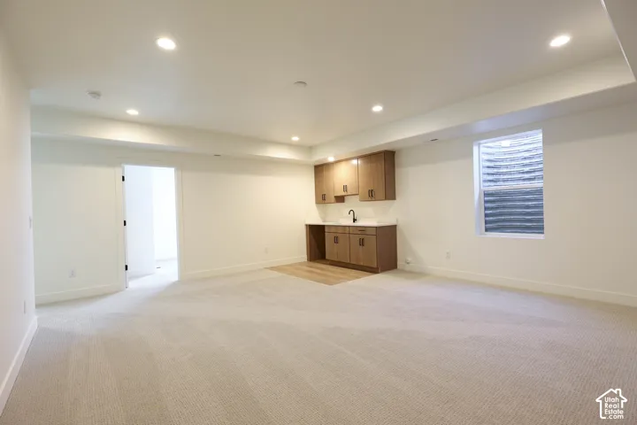 Recessed lighting, wood-finish cabinetry, white countertop, tile backsplash, and light-toned carpeting