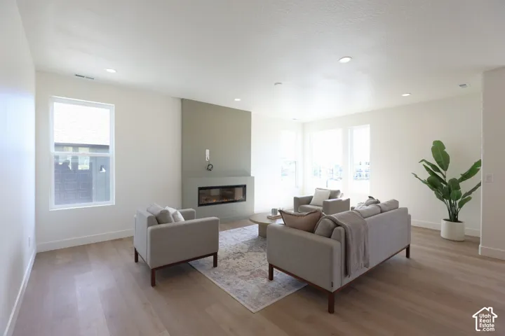 Recessed lighting, wood-finish flooring, multiple windows providing ample natural illumination, and a built-in linear fireplace with a feature wall