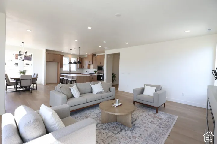 Open-concept living area featuring wood-finish flooring, recessed lighting, and a dining area with a chandelier