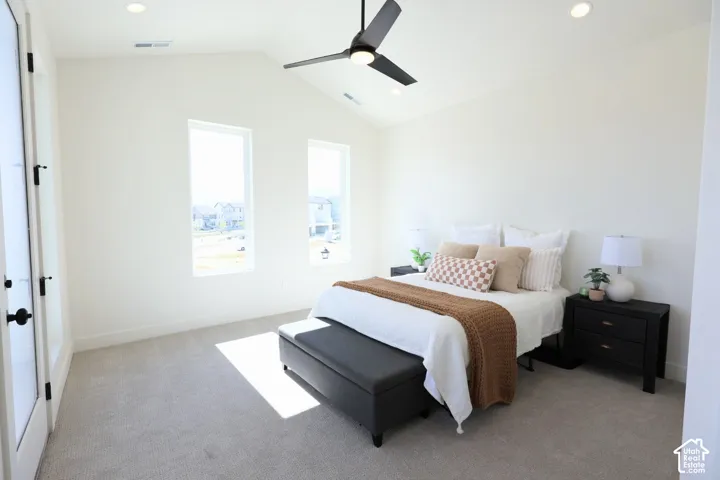 Vaulted ceiling with a ceiling fan, recessed lighting, two vertical windows, and carpet flooring
