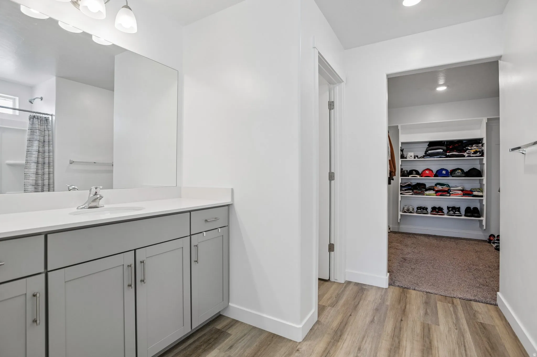 Vanity with light gray shaker cabinetry, integrated sink, and light-toned countertop