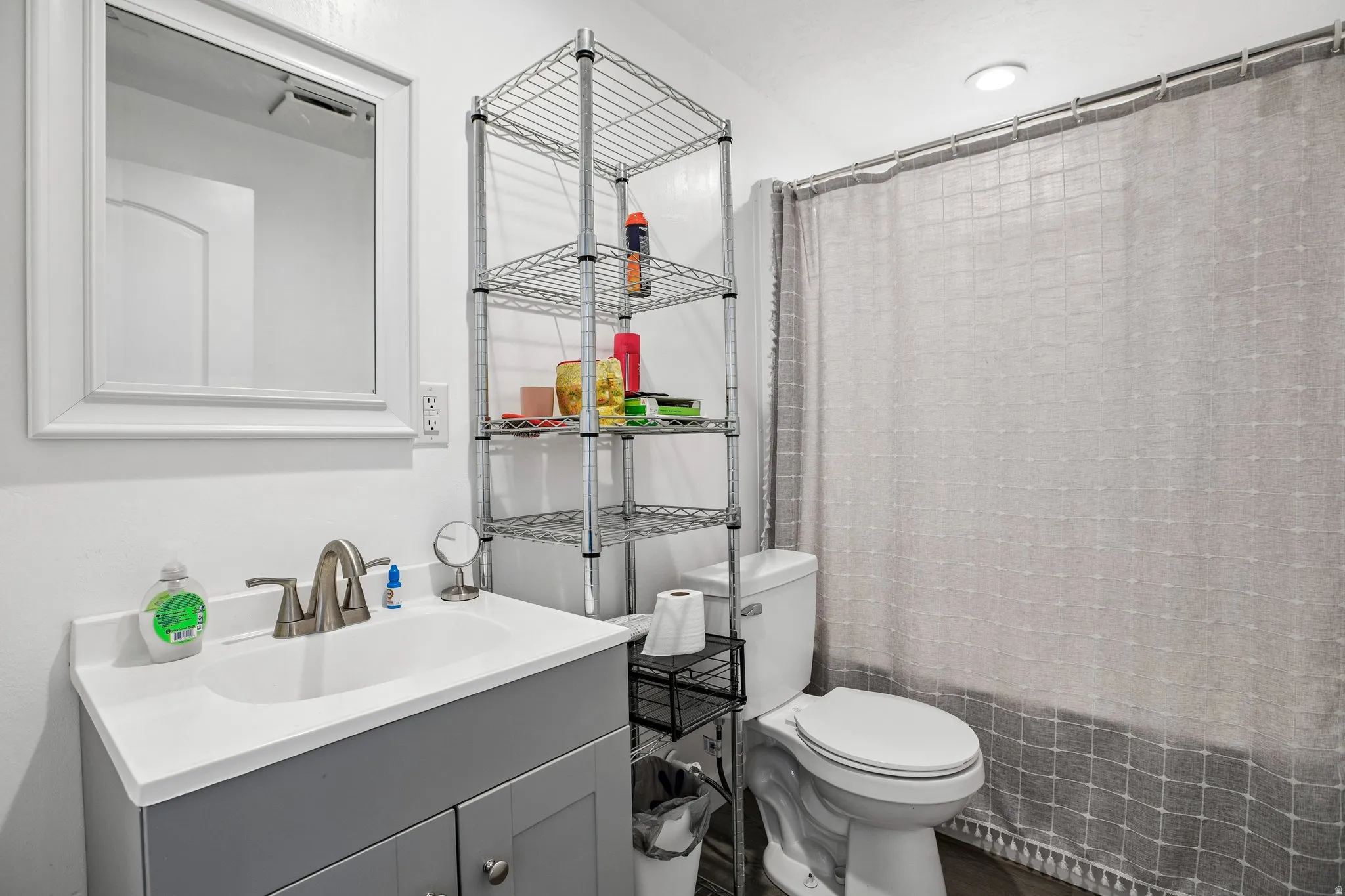 White vanity with a single basin sink, brushed nickel faucet, and a wall-mounted mirror